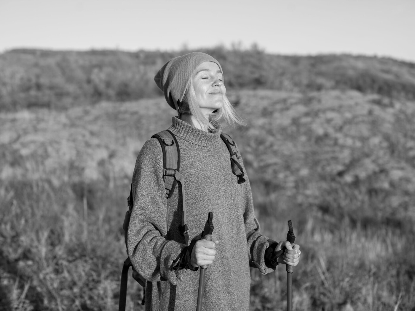 Frau mit Mütze wandert in der Natur und genießt den Augenblick