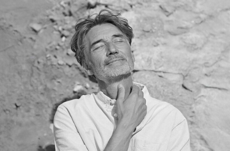 Mann schaut mit geschlossenen Augen der Sonne entgegen