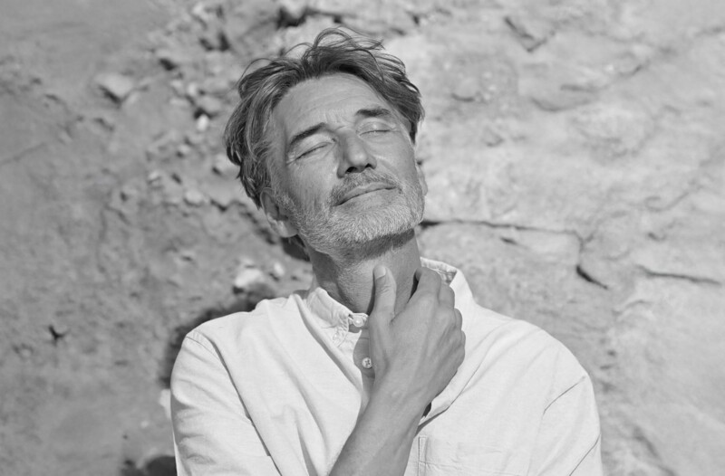 Mann schaut mit geschlossenen Augen der Sonne entgegen